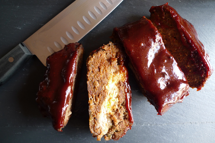BBQ Glazed Mozzarella Meatloaf sliced, showing the mozzarella in the center of the meatloaf. Shown with a large knife.