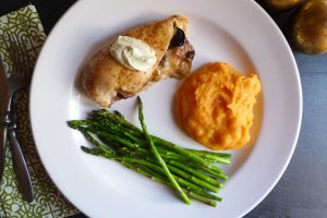 BT Chicken showing a chicken breast stuffed with prosciutto, mushrooms, and Monterey Jack cheese and topped with lime butter sauce. Shown served with roasted red pepper mashed potatoes and asparagus.