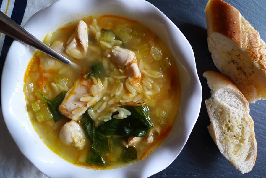 Lemon Chicken Orzo Soup in a bowl, shown with bread.