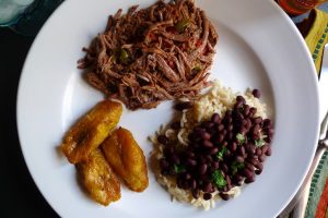 Ropa Vieja with Black Beans and Rice shown served with a side of plantains.
