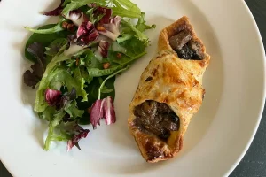 Beef Wellington with Gorgonzola & Shiitake Mushrooms, shown plated with a salad.