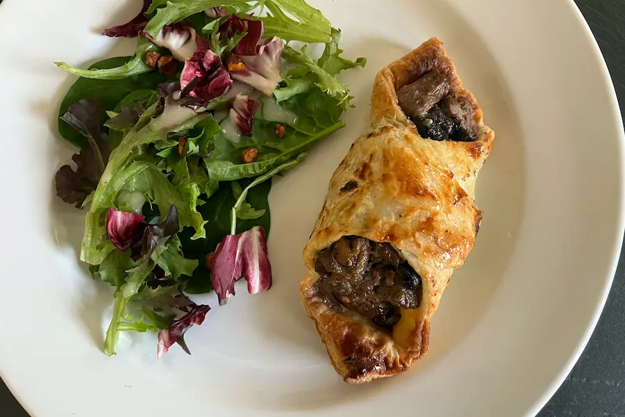 Beef Wellington with Gorgonzola & Shiitake Mushrooms, shown plated with a salad.