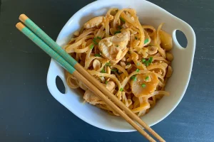Chicken Pad Thai in a bowl shown with chopsticks.