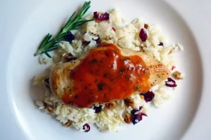 Apple Dijon Chicken with Cranberry Pecan Rice garnished with rosemary sprig.