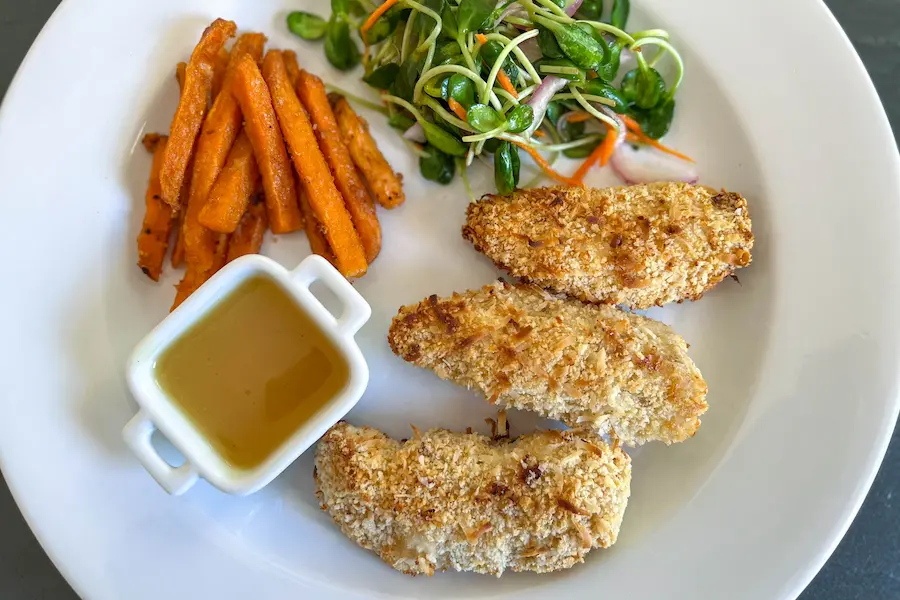 Coconut Chicken Fingers with Orange Sauce shown plated with sides.