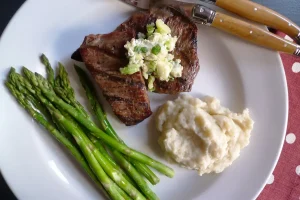 Flank Steak with Bleu Cheese Butter shown plated with sides.