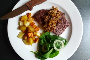 Flank Steak with Bourbon Onions shown plated with vegetable sides.