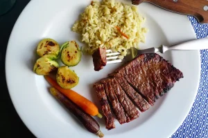 Ginger Sesame Flank Steak with Asian Rice shown plated with vegetable sides.
