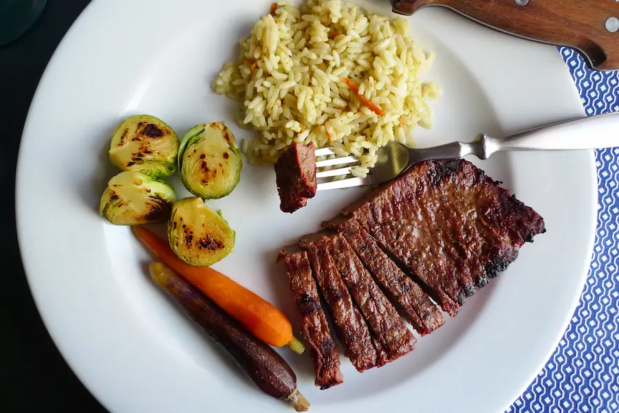 Ginger Sesame Flank Steak with Asian Rice shown plated with vegetable sides.