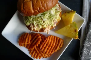 Hawaiian Chicken Sliders shown with sweet potato fries and pineapple garnish.