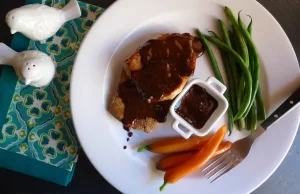 Honey Bourbon Pork Chops shown with sauce and vegetable sides.