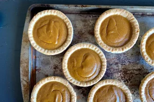 A baking tray with individual pumpkin pies.