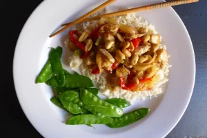Kung Pao Chicken over rice, shown served with a vegetable side dish.