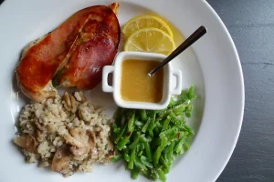 Chicken Saltimbocca plated with sides and lemon slices as a garnish.