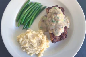 Meatloaf with Mushroom Gravy shown plated with sides.