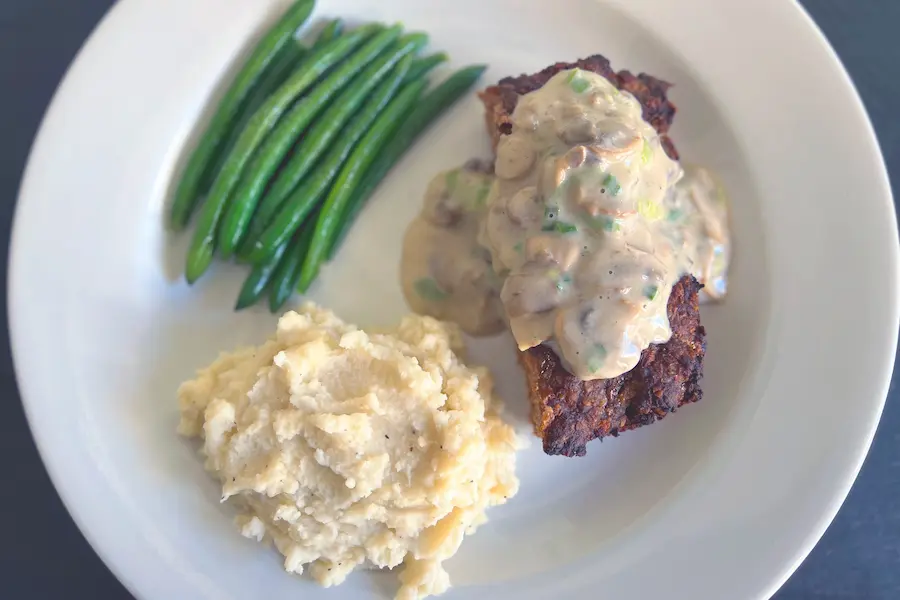 Meatloaf with Mushroom Gravy shown plated with sides.