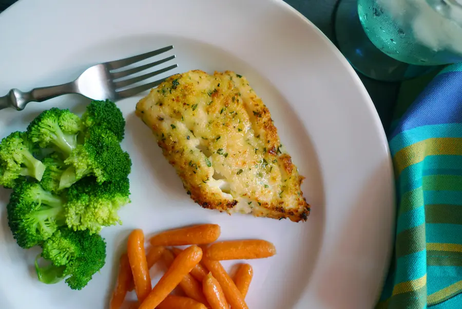 Parmesan Herb Crusted Cod shown plated with vegetable side dishes.