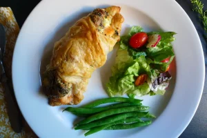 Salmon Florentine Pastry shown plated with vegetable side dishes.