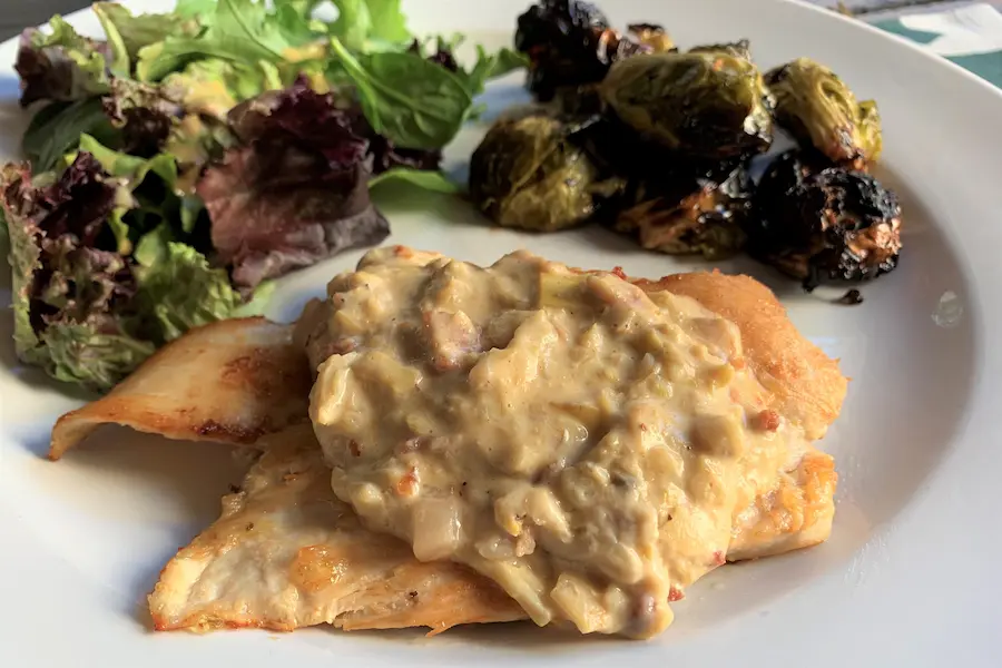 Scallopine Chicken with Artichoke shown plated with side dishes.