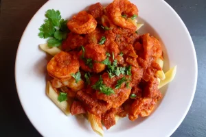 Spanish Shrimp over Penne Pasta garnished with parsley.