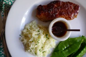 Teriyaki Pork Chops with Pineapple Rice plated with vegetable side dishes.