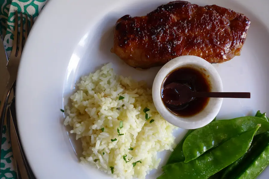 Teriyaki Pork Chops with Pineapple Rice plated with vegetable side dishes.